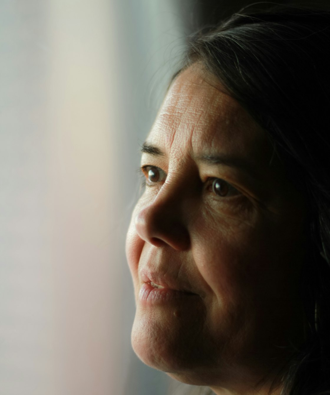 Close portrait of a woman looking out a window